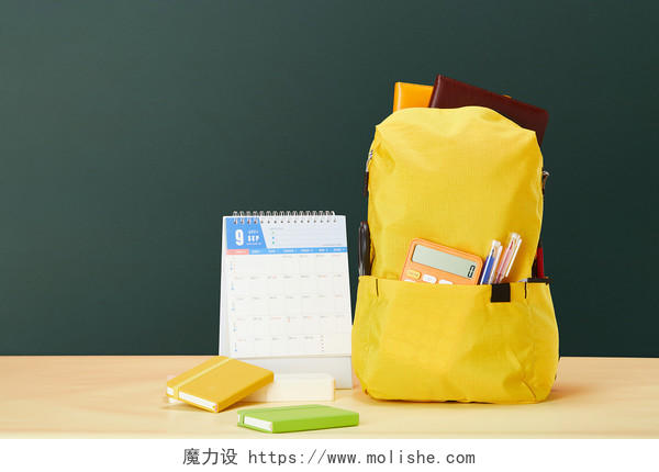 开学季装满文具的黄色书包在教室内黑板前的学习用品场景配图